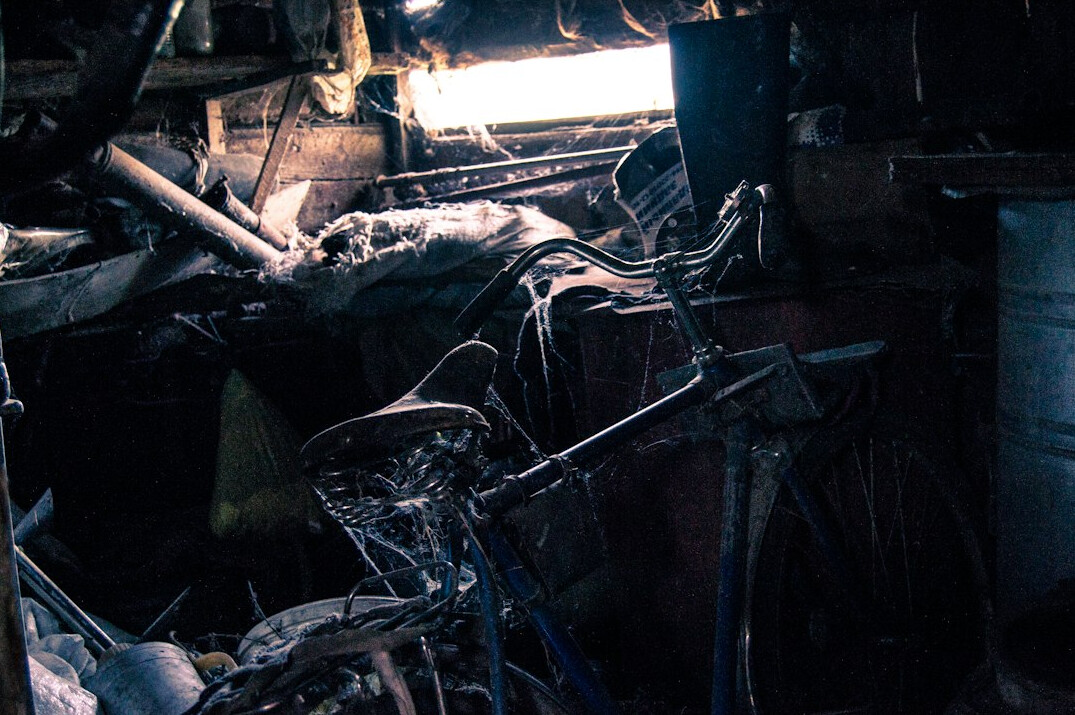 Old classic car covered in dust inside a dark barn