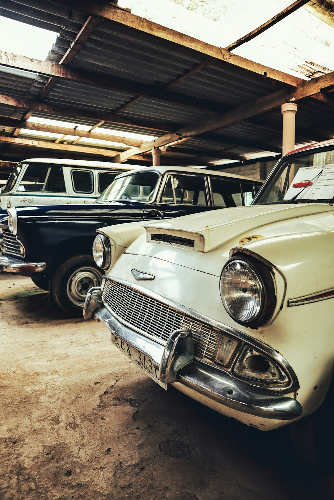 Row of vintage cars parked inside an old brick garage