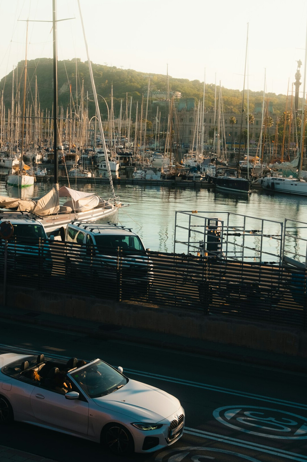 Classic sports car driving on a coastal road at sunset